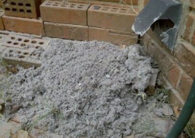 Dryer vent cleaning outside of home with vent lint and bricks.