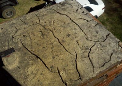 Badly cracked chimney crown with vehicles in the background.