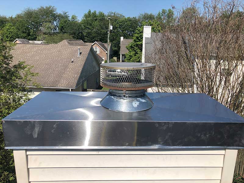 Prefab stainless steel crown cover with homes and trees in the background.