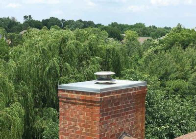 Chase Cover on brick chimney with beautiful trees in the background.