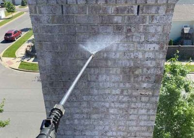 Chimney Waterproofing - hand holding wand, cap on top buildings in the back ground.