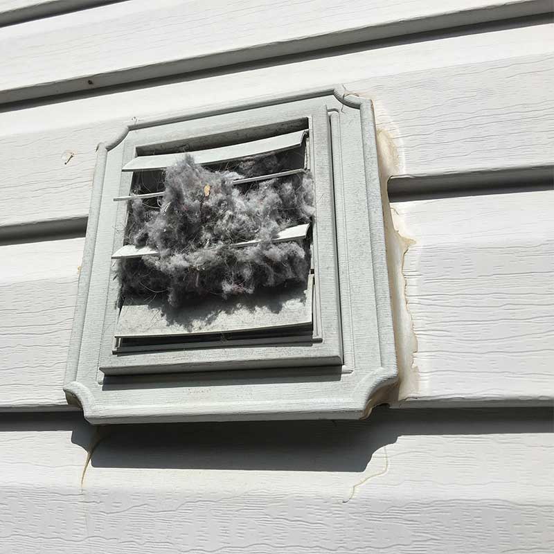 Outside dryer vent with lint falling out.