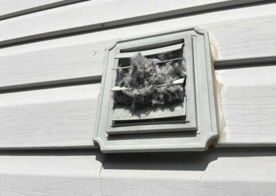 Outside dryer vent with lint falling out.