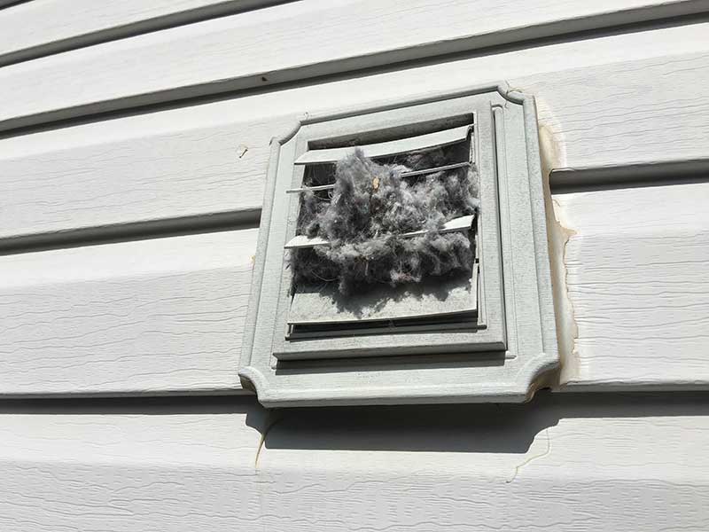 Outside dryer vent with lint falling out.