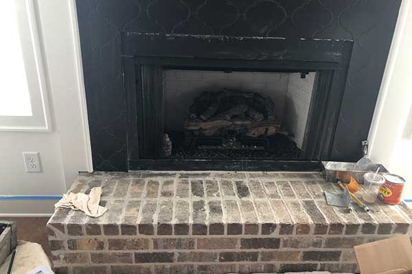 New fireplace construction with mortar joint equipment sitting on a stone hearth.