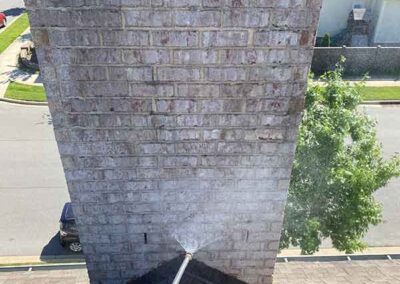 Wand spraying waterproofing on chimney with street in the background.
