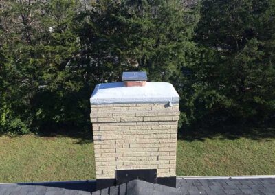 Waterproofing your chimney is essential. This chimney has a nice cover and cap. There are plenty of trees in the background.