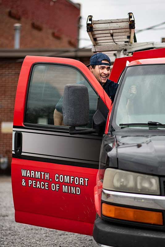 Original photo of tech entering truck - Sweeps and Ladders Tech smiling getting into work truck with ladder on top.